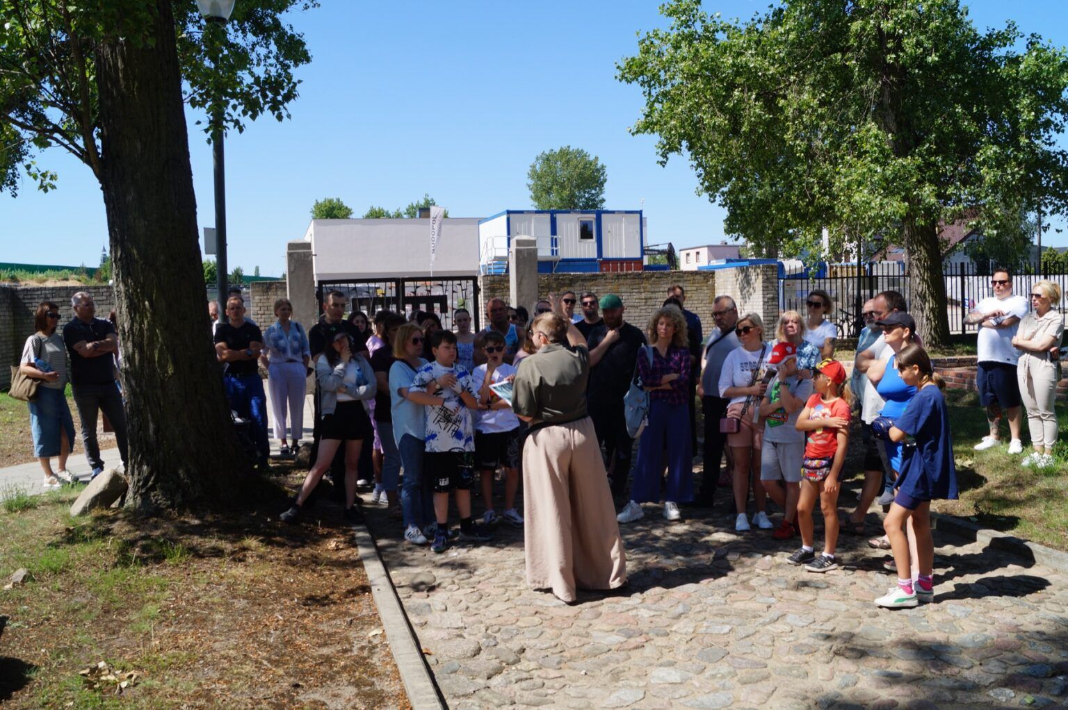 Grupa osób zwiedza teren dawnego niemieckiego obozu karno-śledczego w Muzeum Męczeństwa w Żabikowie z przewodnikiem.
